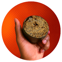 a person holding a cup of coffee with a donut in it