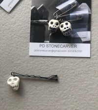 a pair of skull hair pins and a business card