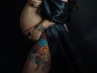 a pregnant woman with tattoos posing on a black background