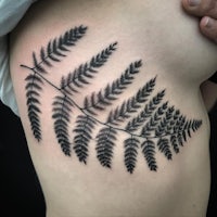 a black and white tattoo of a fern leaf