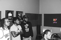 a black and white photo of a group of men in a recording studio