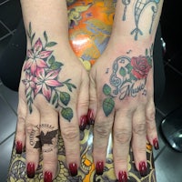 a woman's hands with tattoos of roses and flowers
