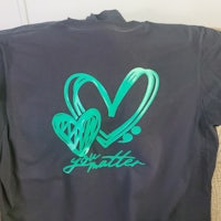 a black t - shirt with a green heart on it