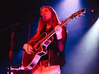 a girl playing an acoustic guitar on stage
