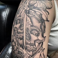 a tattoo of a skull and flowers on the arm