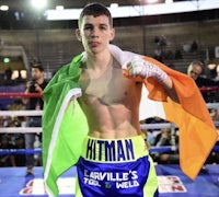 irish boxer hitman poses with an irish flag in front of a boxing ring