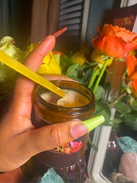 a hand holding a jar of face cream and flowers