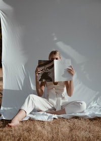 a woman sitting on the ground reading a magazine