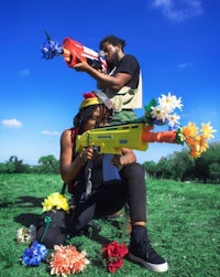 two people playing with a nerf gun in a field