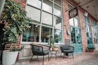 the front of a brick building with chairs and potted plants