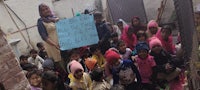 a group of children holding a sign in front of a building