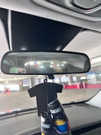 the rear view mirror of a car with a bottle hanging from it