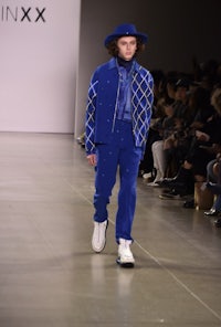 a man wearing blue pants and a hat on the runway