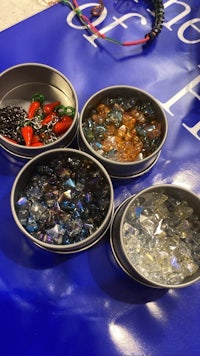 four tins of different colored beads on a table