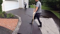 a man cleaning a driveway with a broom