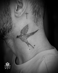 a black and white photo of a man with a bird tattoo on his neck