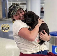 a woman is holding a puppy in an airport