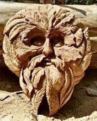 a wood carving of a green man on a log