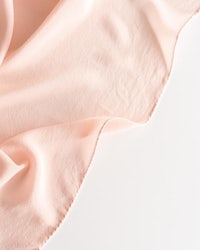 a pink silk scarf on a white surface
