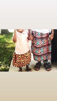 two children standing next to each other wearing colorful skirts