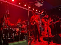 a group of people playing music on stage in front of a red light