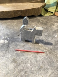 a small statue of a dog with a red stick next to it