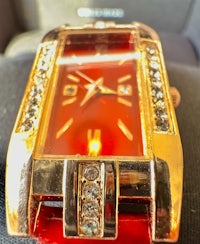 a red and gold watch with crystals on it
