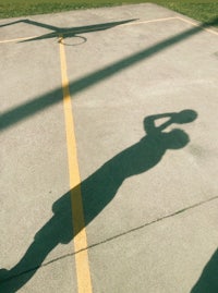 a shadow of a basketball player on a court