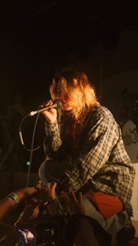 a man in a plaid shirt singing into a microphone
