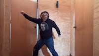 a man in a hoodie standing in a doorway