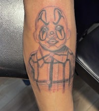 a tattoo of a clown on a leg