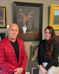 a man and woman standing in front of framed art
