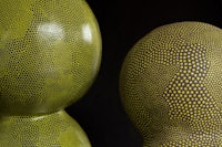 two yellow and black dotted vases on a black background