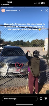 a woman is standing in front of a fence with a car in the background