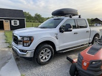 a white ford f - 150 truck parked in front of a barn