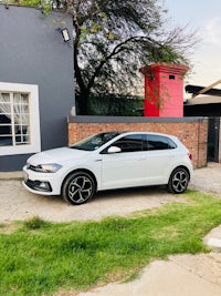 a white volkswagen polo parked in front of a house