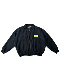 a black bomber jacket with a yellow patch on it