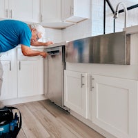 a man cleaning a kitchen with a vacuum