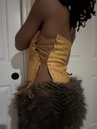 a black woman wearing a yellow corset with fur