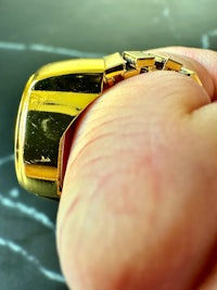 a person's hand holding a gold ring