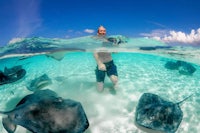 a man is swimming with sting rays in the water