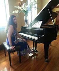 a woman in a blue dress sitting next to a black grand piano