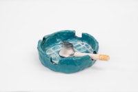 a blue ashtray with a cigarette in it