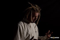 a man with dreadlocks in front of a black background