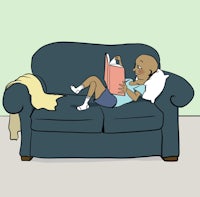 a person laying on a couch reading a book