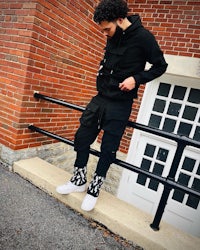 a man wearing a black hoodie and white sneakers