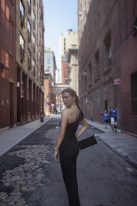 a woman in a black dress standing on a street