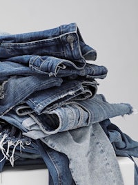 a pile of blue jeans on a white background