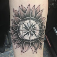 a tattoo of a compass with a sunflower