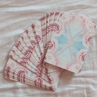 tarot cards laying on a bed with pink and blue designs